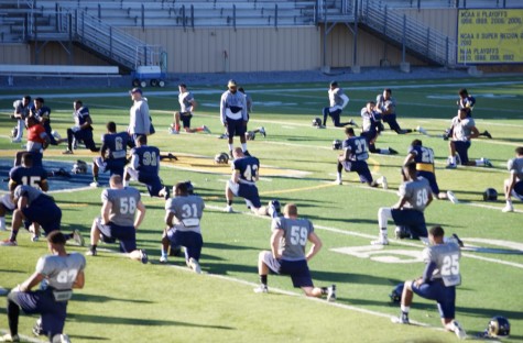 Before starting practice, the football players stretch throughly in order to perform their best.