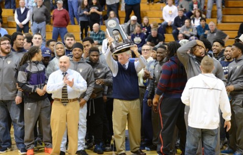Head football coach Monte Cater holds up the Division 2 runner up trophy in a ceremony at halftime 