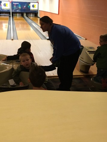 Early Learning Center Staff Dana Cipala helps on of the children switch from regular sneakers to bowling shoes.